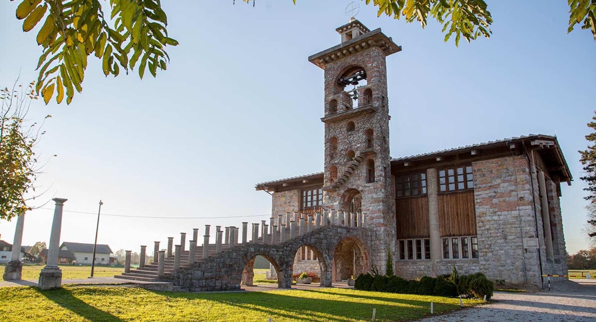 Ikonična zunanjost Cerkve sv. Mihaela, ki prikazuje Plečnikov inovativni zvonik in obokano stopnišče.