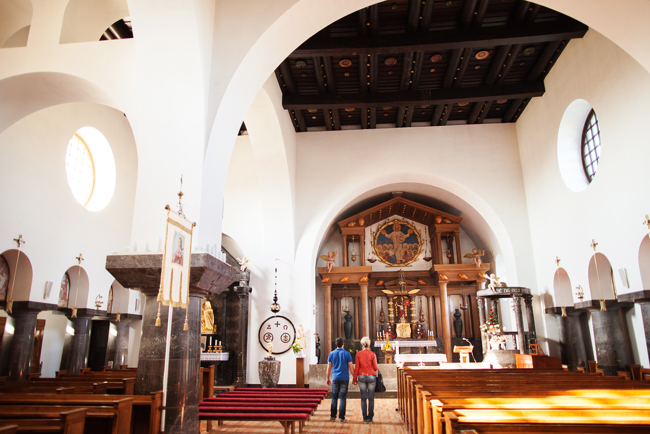 Vabljiva notranjščina cerkve Bela golobica, ki prikazuje leseni strop okrašen z lokalnimi keramičnimi krožniki.